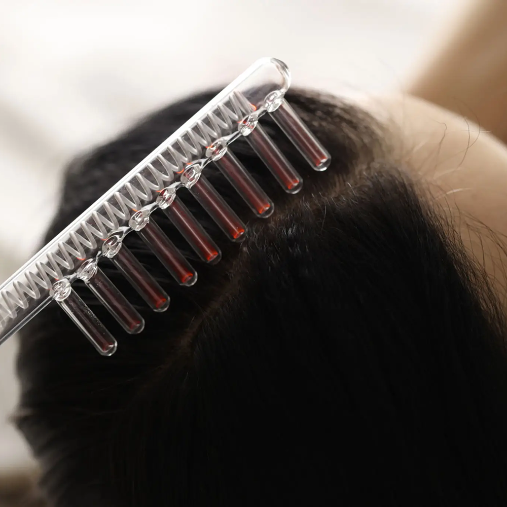 A close-up of a scalp with a comb lifting hair sections.