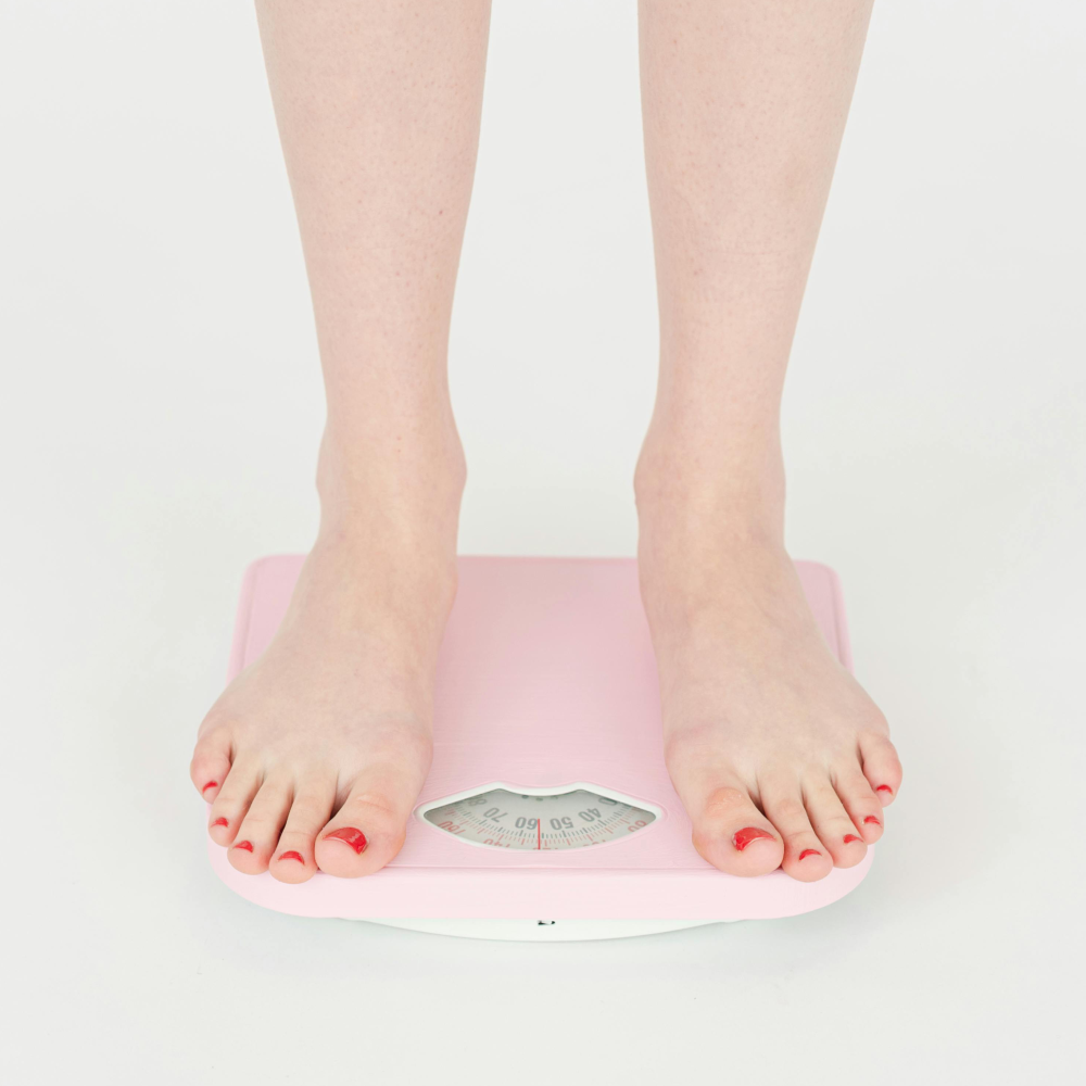 Person standing on a pink bathroom scale.
