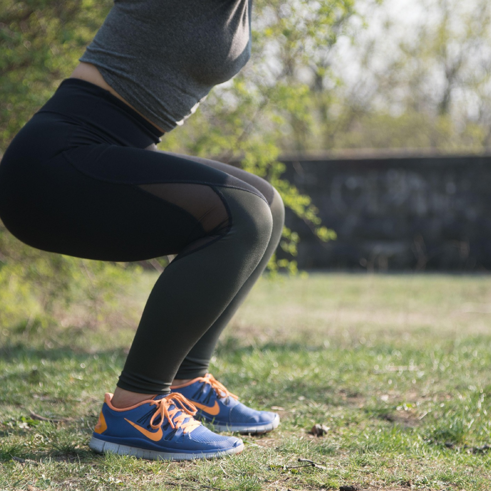 Person doing a squat exercise outdoors in athletic wear.